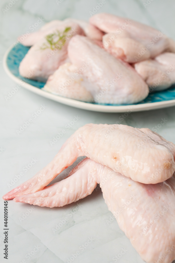 Raw chicken wings with herbs, over a blue plate, green background Raw chicken wings with herbs, over a blue plate, green background