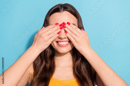 Photo portrait girl pretty cheerful smiling covering eyes with hands isolated pastel blue color background copyspace © deagreez