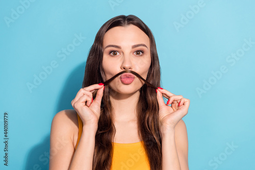Photo portrait girl with long hair keeping fake mustache on pouted lips isolated pastel blue color background