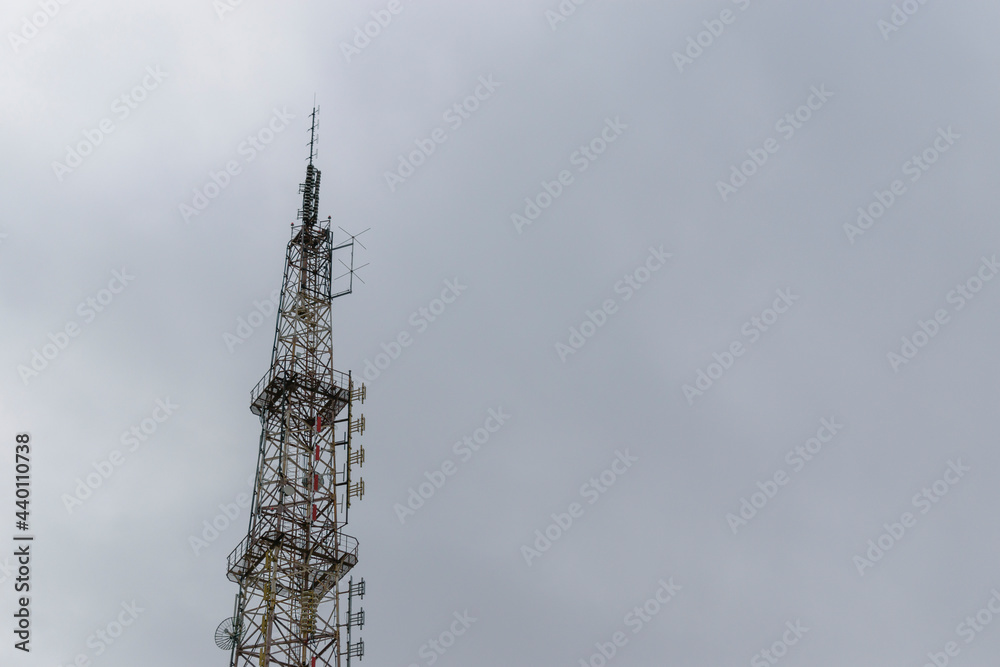 Telecommunication tower. Metal constructions. Transmitting antennas. The background is a cloudy sky.
