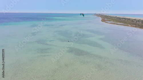 Fly over from a height of a kitesurfer trying to get to his feet and catch a favorable wind on a salt lake near the sea shore