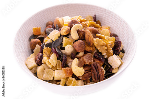 a mixture of chopped dried fruits and berries, nuts in a white dish on a white background . Isolated items and products.