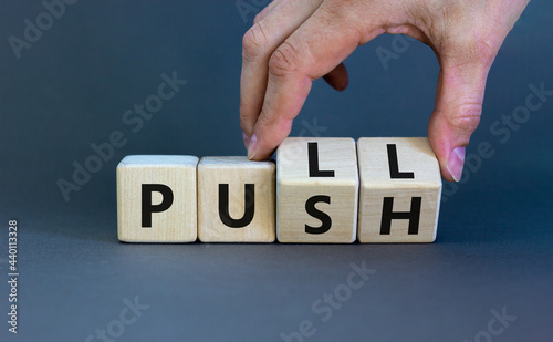 Pull or push symbol. Businessman turns wooden cubes and changes the word 'push' to 'pull'. Beautiful grey background, copy space. Business and pull or push concept. photo