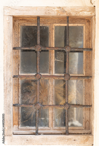 An ancient window with wooden frames and iron bars .