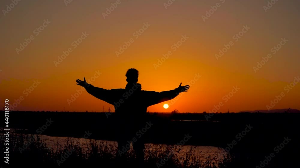 Man open his arms to take a breath in a natural places in font of the sun at the sunset time Man open his arms to take a breath in a natural places in font of the sun at the sunset time