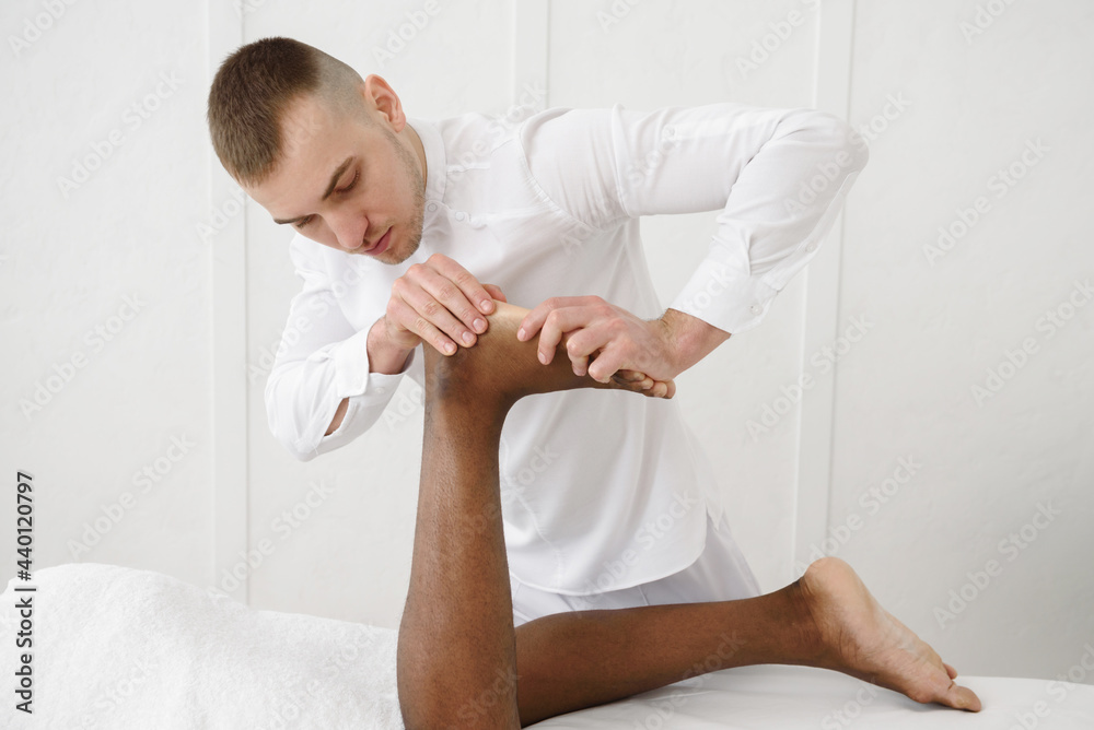 Fototapeta premium African american man having foot massage in spa, white background. Copy space, closeup