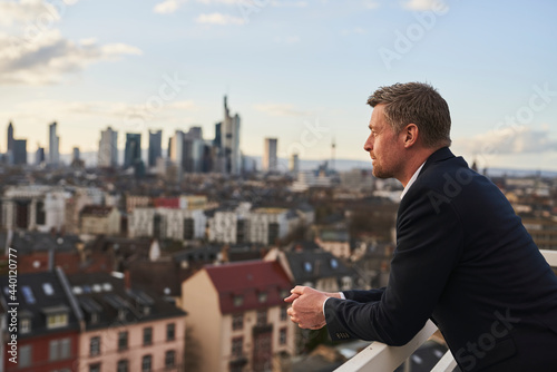 Thoughtful mature businessman standing at rooftop in city