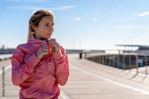 Thoughtful woman holding jacket zipper while looking away photo