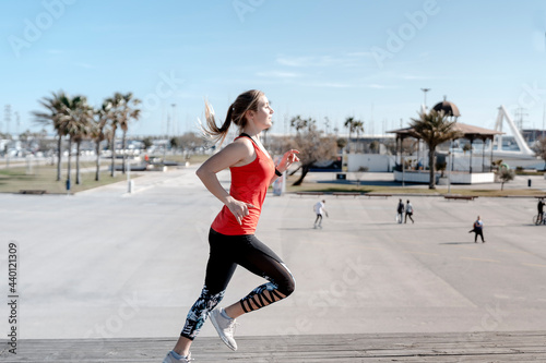 Female jogger running on pier during sunny day photo