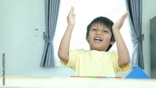 Happy Asian preschooler boy kid laughing and clapping his hands.