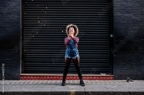 Happy woman playing with party popper on footpath