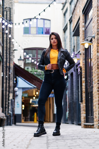 Confident woman in leather jacket standing on street photo