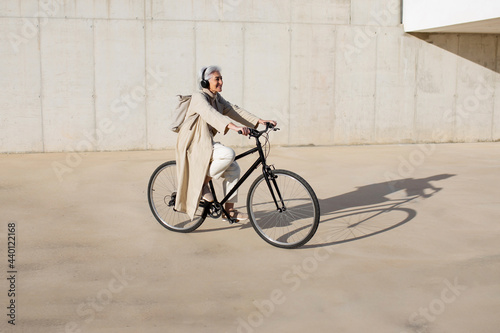 Mature woman riding bicycle on footpath during sunny day photo