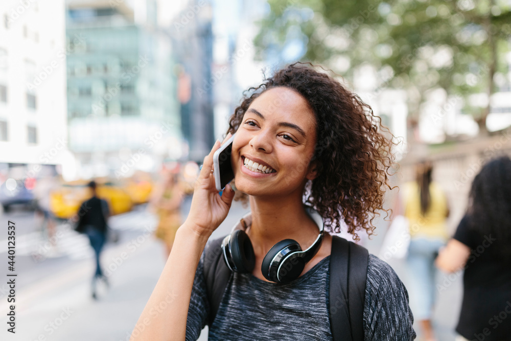Happy woman looking away while talking on smart phone in city Happy woman looking away while talking on smart phone in city