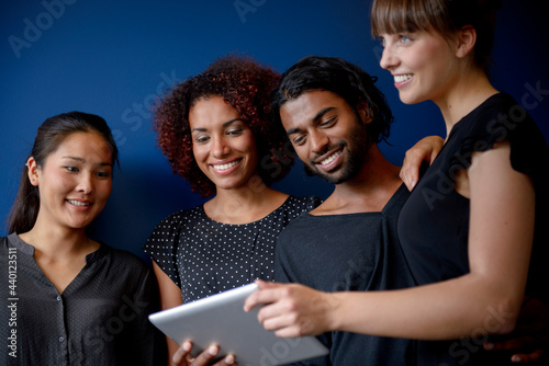 Smiling international male and female professionals working on digital tablet in front of blue background photo