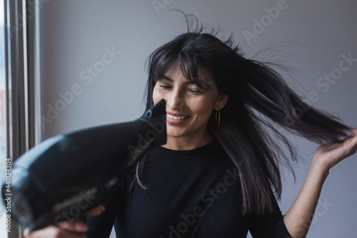 Beautiful woman using hair dryer at home