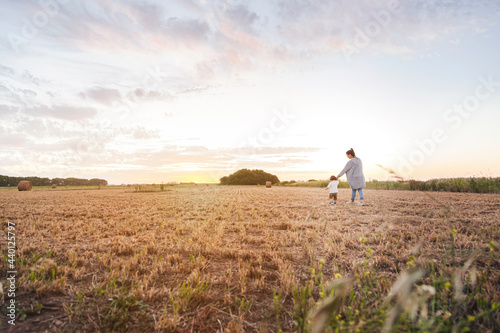 Wallpaper Mural Mother walking with baby son through harvested field at sunset Torontodigital.ca