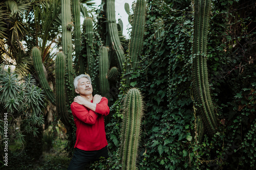Mature man hugging self while standing in cactus garden photo