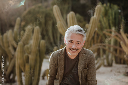 Smiling mature man with cactus garden in background