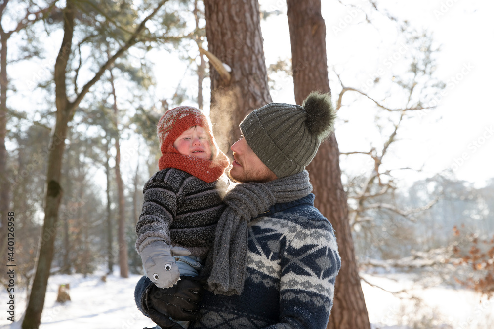 Father in warm clothing looking at crying son during winter Father in warm clothing looking at crying son during winter