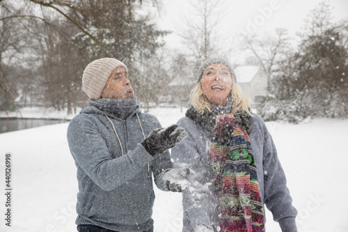 Senior couple throwing snow while playing during winter photo