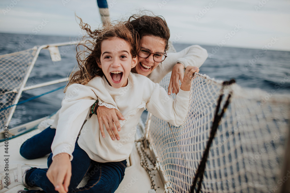 © Gala Mart√≠nez L√≥pez/Westend61 - Laughing mother with excited daughter on sailboat during vacation