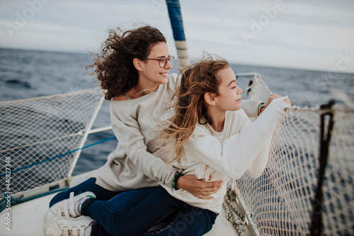 Mother and daughter looking at view while traveling through sailboat in sea during vacation photo
