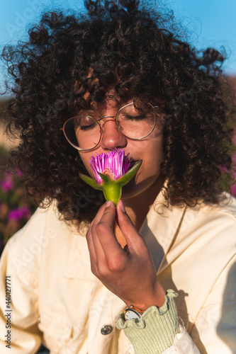 Young woman with eyes closed smelling carpobrotus edulis flower photo