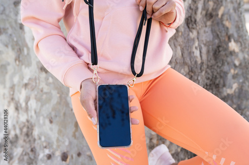 Woman holding smart phone by tree