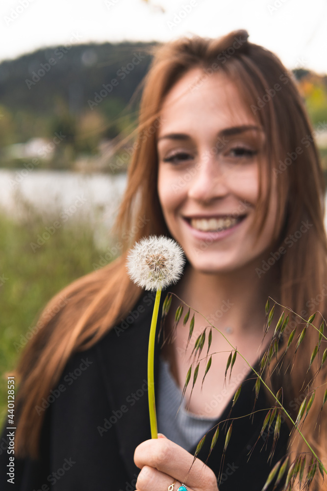 Beautiful woman smiling while looking at blowball Beautiful woman smiling while looking at blowball