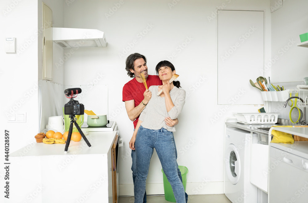 Mature couple enjoying vlogging while standing in kitchen at home Mature couple enjoying vlogging while standing in kitchen at home