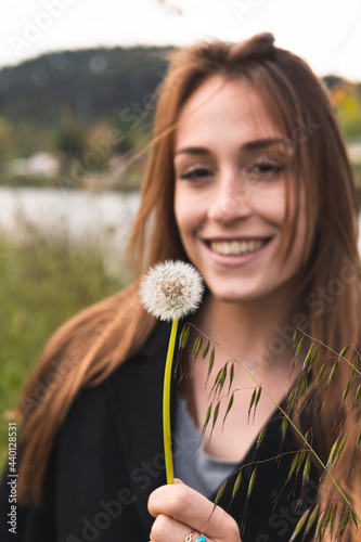 Beautiful woman smiling while looking at blowball