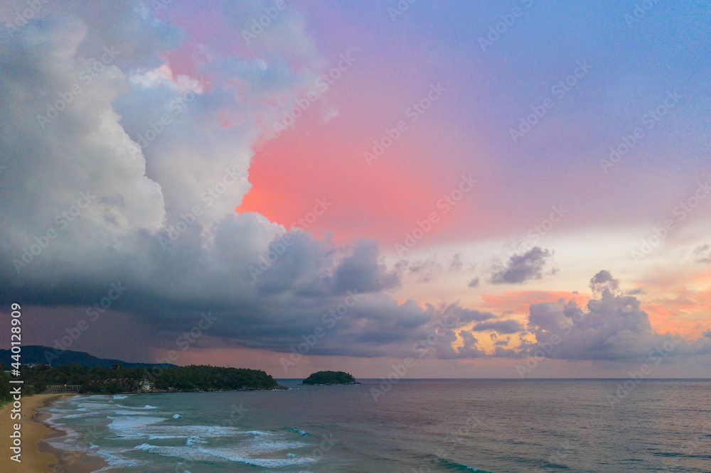 ..aerial view white rain cloud on pink sky in sunset at Karon beach Phuket..white rain cloud,pink sky, blue sea, and clear sand landscape. Paradise beach.