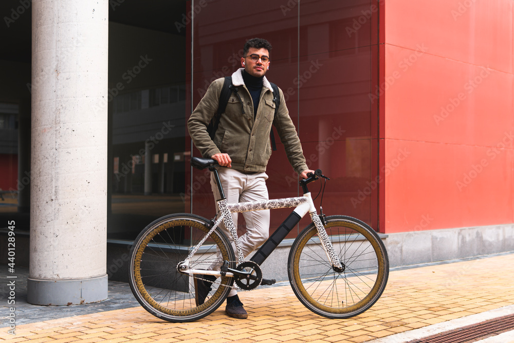 Handsome businessman with bicycle standing on footpath