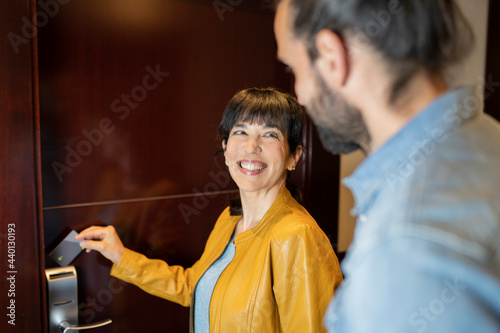 Smiling woman opening door with card key in hotel photo