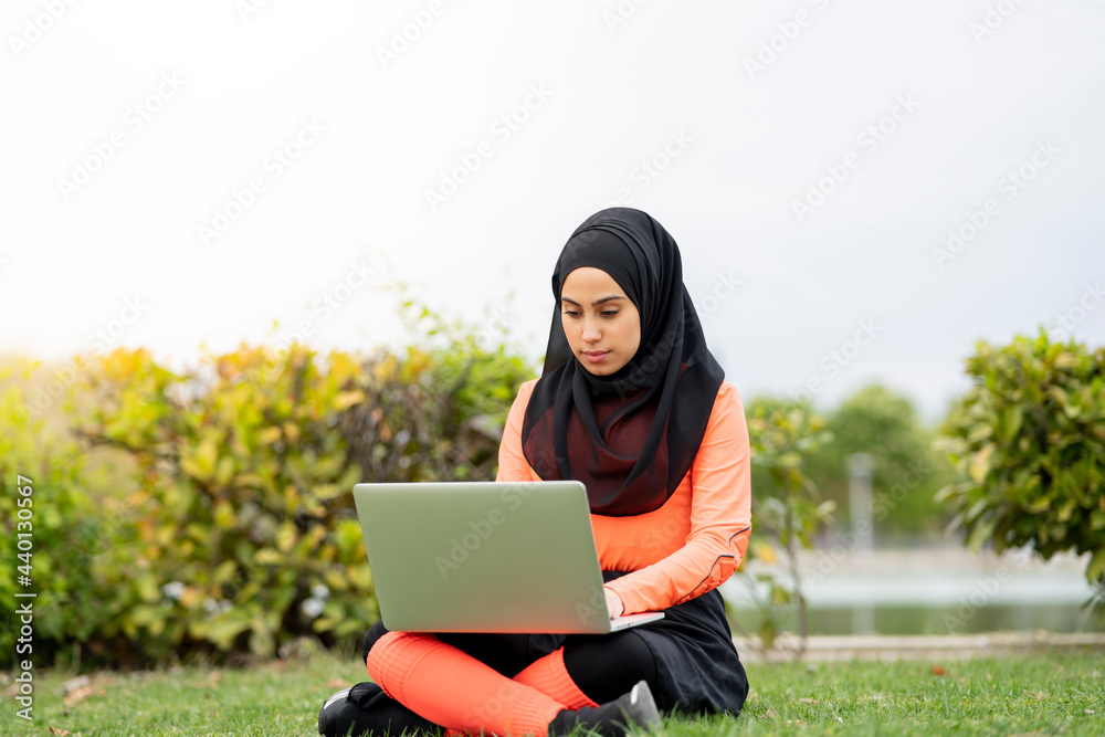 Young woman using laptop while sitting in public park Young woman using laptop while sitting in public park