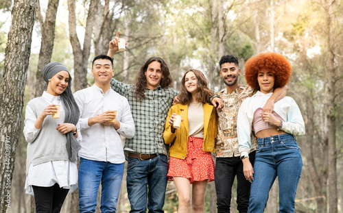 Cheerful male and female friends holding reusable glass in forest photo