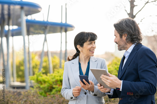 Smiling male and female professionals looking at each other in ofiice park photo