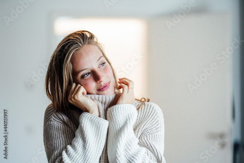 Beautiful woman in sweater looking away at home