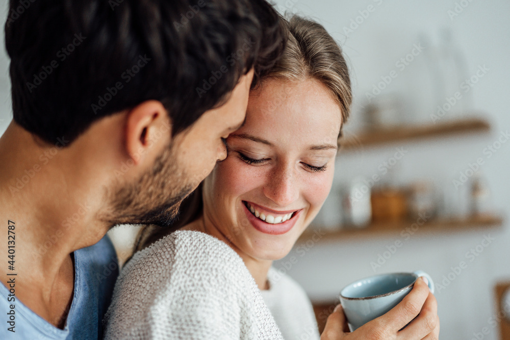 Young man embracing smiling woman at home Young man embracing smiling woman at home