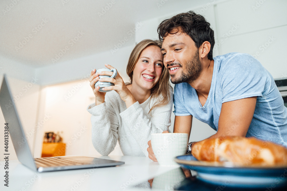 Happy young couple having coffee while leaning on kitchen counter at home Happy young couple having coffee while leaning on kitchen counter at home