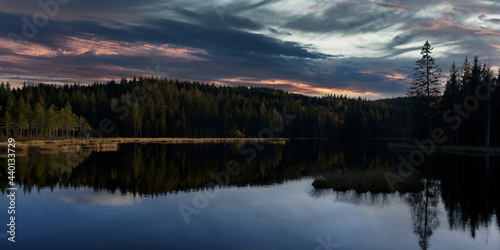 Sunrise over the lake. The sky is dramatic and on fire. Shot in Nordmarka, Oslo, Norway. 