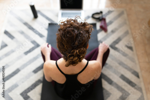 Woman on exercise mat practicing yoga at home photo