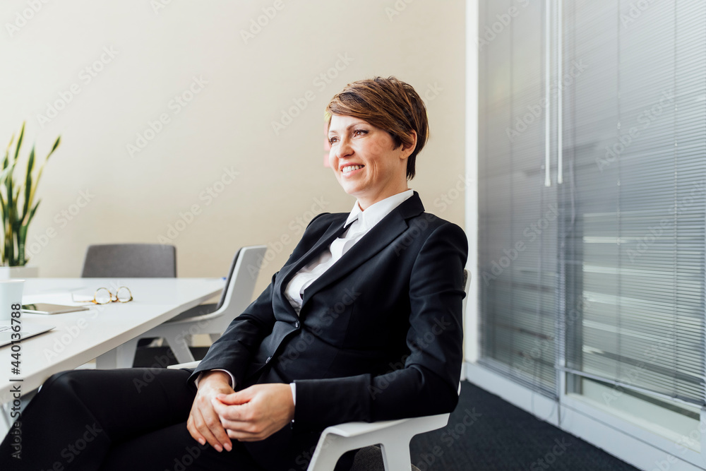 © Eugenio Marongiu/Westend61 - Smiling female business professional day dreaming while sitting on chair in office
