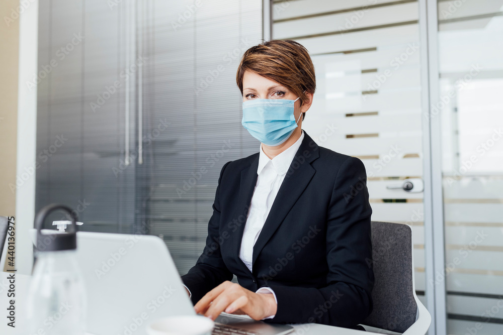Female entrepreneur with brown hair working on laptop in office Female entrepreneur with brown hair working on laptop in office