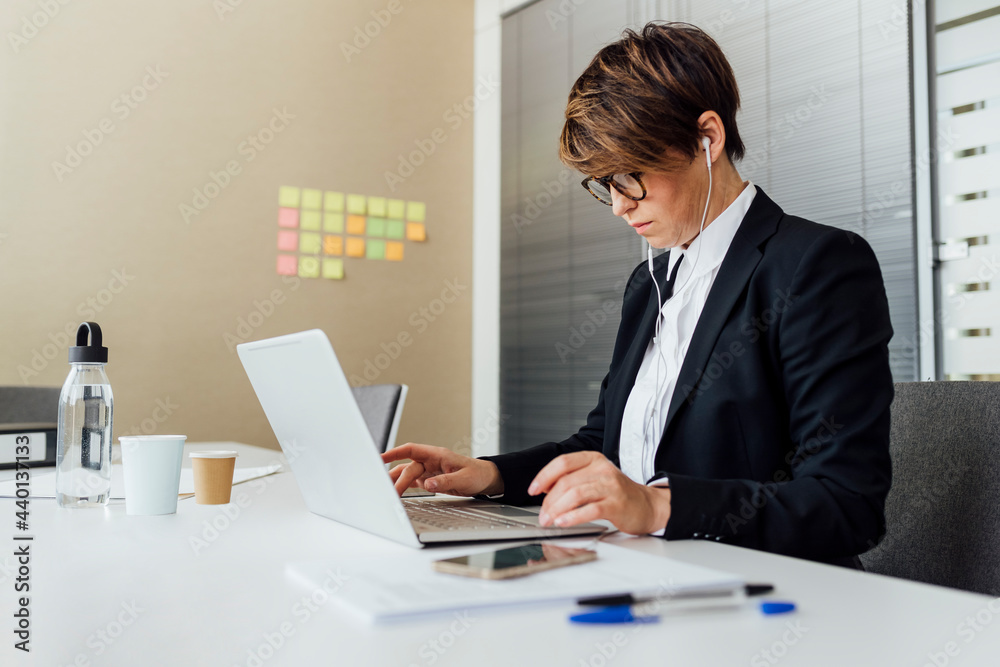 Female business professional using laptop at desk in office Female business professional using laptop at desk in office