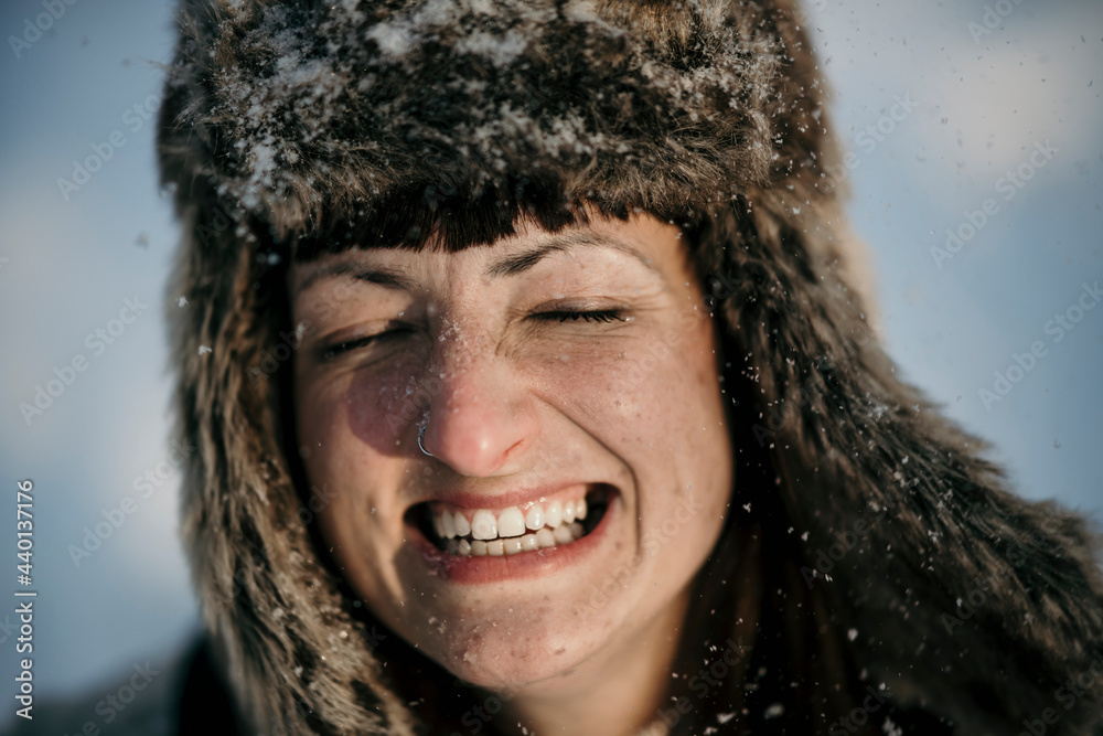 Mid adult woman wearing hunters cap smiling with eyes closed Mid adult woman wearing hunters cap smiling with eyes closed