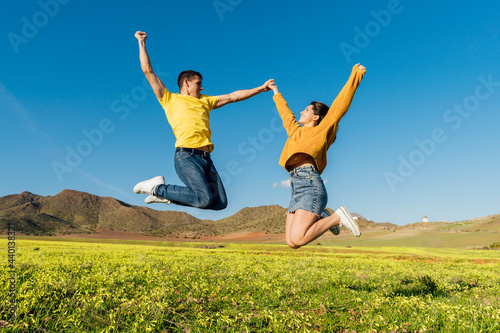 Young couple jumping with joy over grass