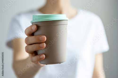 Woman holding disposable cup in front of white background photo