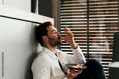 Man licking fingers while eating food at home photo